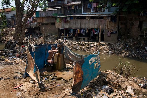 A Bukit Duri resident hand-pumping groundwater in a public bathing space by the Ciliwung river waterwoes2.jpg